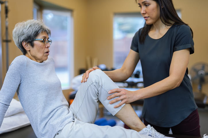 A physical therapist working with an elderly patient. 