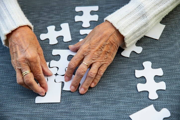 Is Memory Care Considered Skilled Nursing In Utah? 1 Focus in on an elderly person's hands fitting puzzle pieces together.