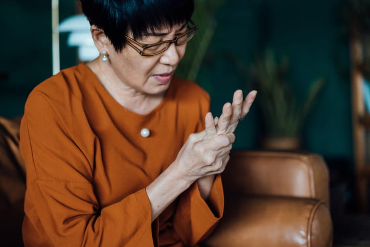 A woman massaging her hand due to a chronic condition.