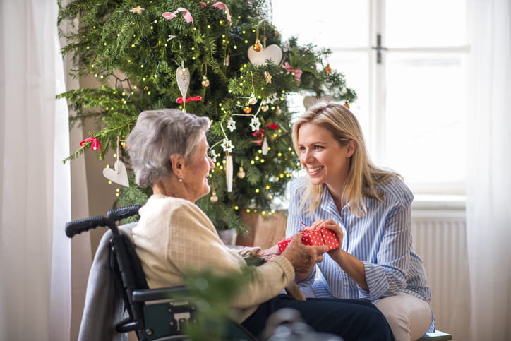 How To Navigate The Holidays With A Loved One In Skilled Nursing 1 A woman with her elderly mother in front of a Christmas tree at a skilled nursing facility.