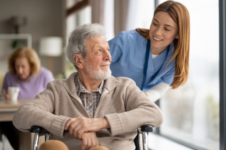 A joyful moment captured as a caregiver shares a smile with an elderly man, highlighting the importance of companionship and care.