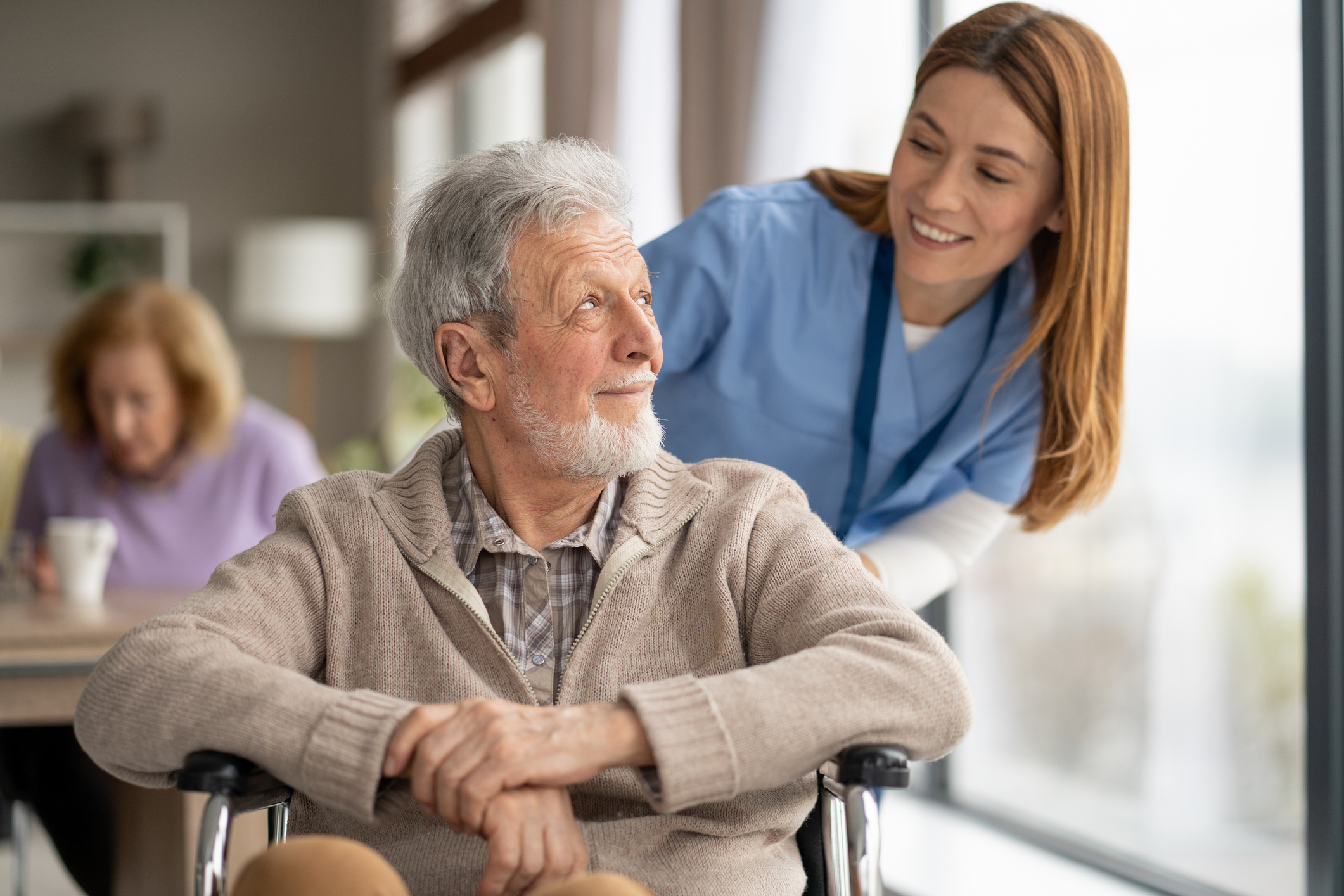 A joyful moment captured as a caregiver shares a smile with an elderly man, highlighting the importance of companionship and care.