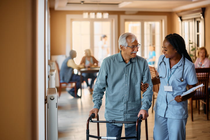 A nurse assists a patient with a walker at a skilled nursing facility.