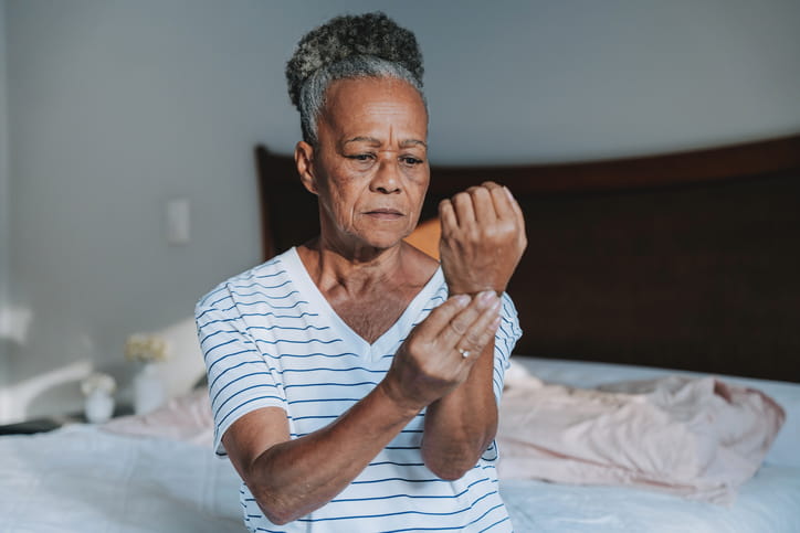An elderly woman holding her wrist due to arthritis pain.