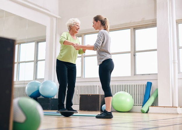 A physical therapist helps a senior with her balance.