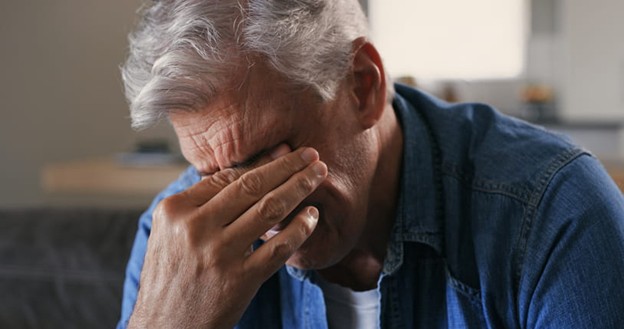 A senior rubs his eyes due to stress from extreme fatigue.