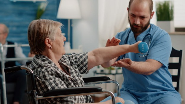 A physical therapist works with a senior in a wheelchair to help her with her chronic conditions.