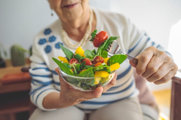 An elderly woman shows off her salad.