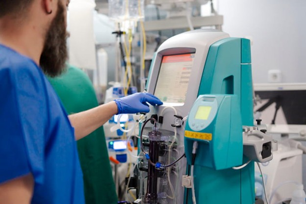 A medical provider alters the settings on a dialysis machine.