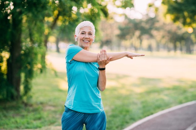 A senior smiles as she stretches.