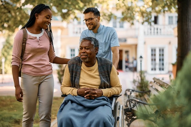 The Role Of Family In Senior Care 2 A woman visits her senior family member at a skilled nursing facility as the staff member assists outside.