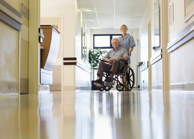 What Life Is Like At A Skilled Nursing Facility 2 A nurse assists a patient in a wheelchair at a skilled nursing facility.