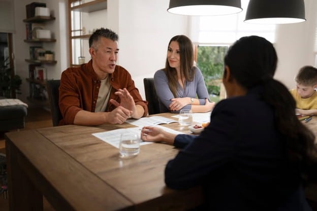 Managing Sibling Disagreements About A Parent's Care Plan 2 Three adults discuss their parent's care plan as a kid draws at the table.
