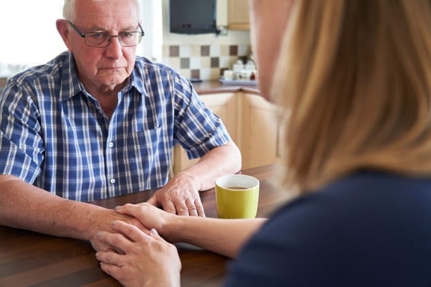 What Happens When A Loved One Refuses Help? 2 A daughter holds the hand of her elderly parent as she tries to help him.
