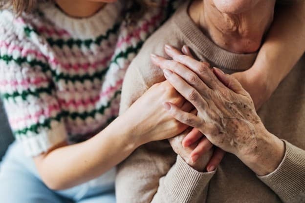 How Family Members Can Support Recovery After A Surgery 2 A daughter wraps her arms around her elderly mother.