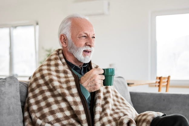 What To Bring to a Skilled Nursing Facility 2 An elderly man with a blanket around his shoulders drinks a cup of coffee.